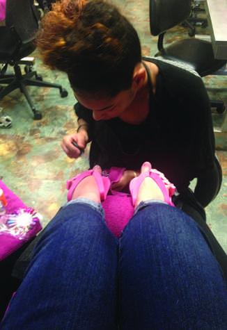 Cosmetology student Channel Jones giving EvCC student Brittanie Pervier a pedicure.