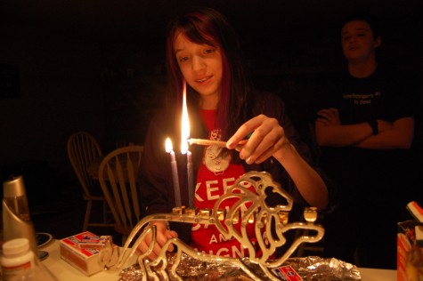 Molly lighting her family menorah as her brother watches closely.