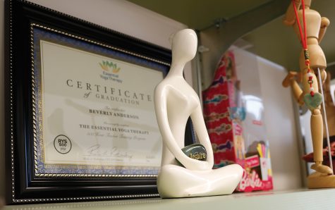 A yoga figurine sits in front of teacher Beverly Anderson’s yoga teaching certificate from Essential Yoga Therapy.