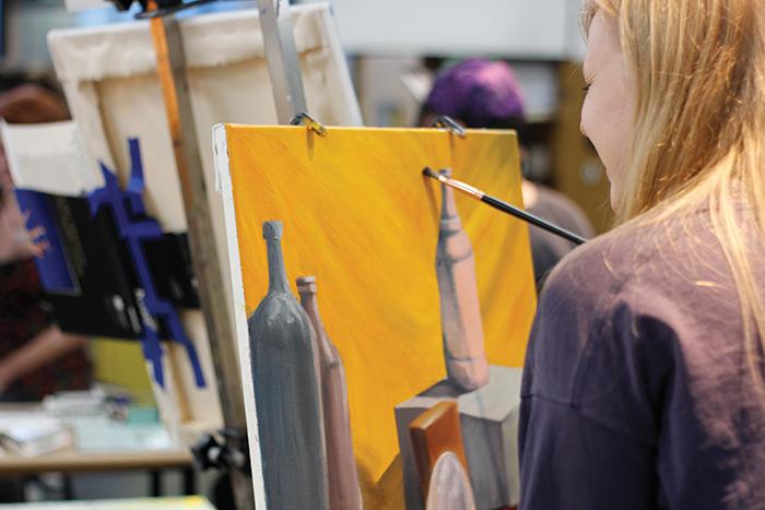 While finishing a still life painting, Loomis laughs with surrounding artists in the studio.
