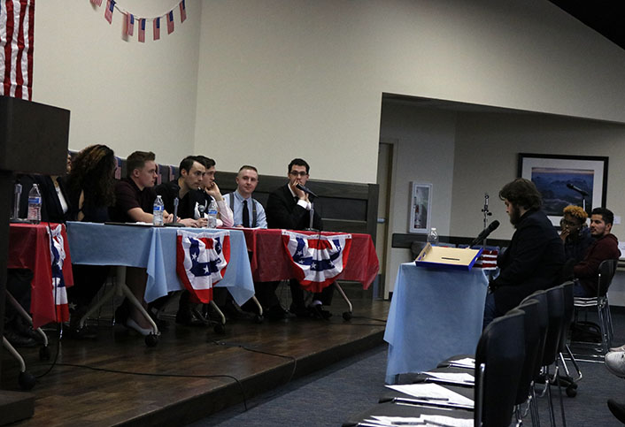 John Yeager, right, moderates the event during the second round of the debate. The Republicans sit at the blue table, and the Libertarians sit at the red table to the right.