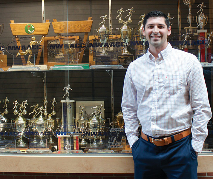 Garet Studer, EvCC’s Athletic Director, poses in front of the  tness center’s trophy case.