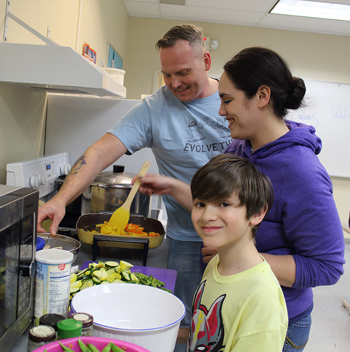 Jarrett Morris (front) has been coming to the Community Kitchen Club since the club’s first dinner with his mom, Mele Metcalf (center) who is a student at EvCC. Metcalf says they haven’t missed a dinner yet. Newcomer Rory Featherston (rear), an Army Photojournalist, joined in the cooking fun. This was his first dinner with the club.
