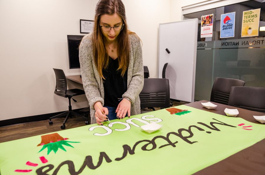 Sofie Havlerson paints posters in preparation for the Midterms Succ event on Monday, May 13.