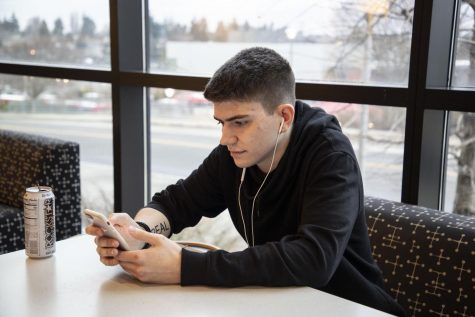 EvCC student, John Roberts, listening to music on his smartphone via headphones on the second floor of White Horse Hall.