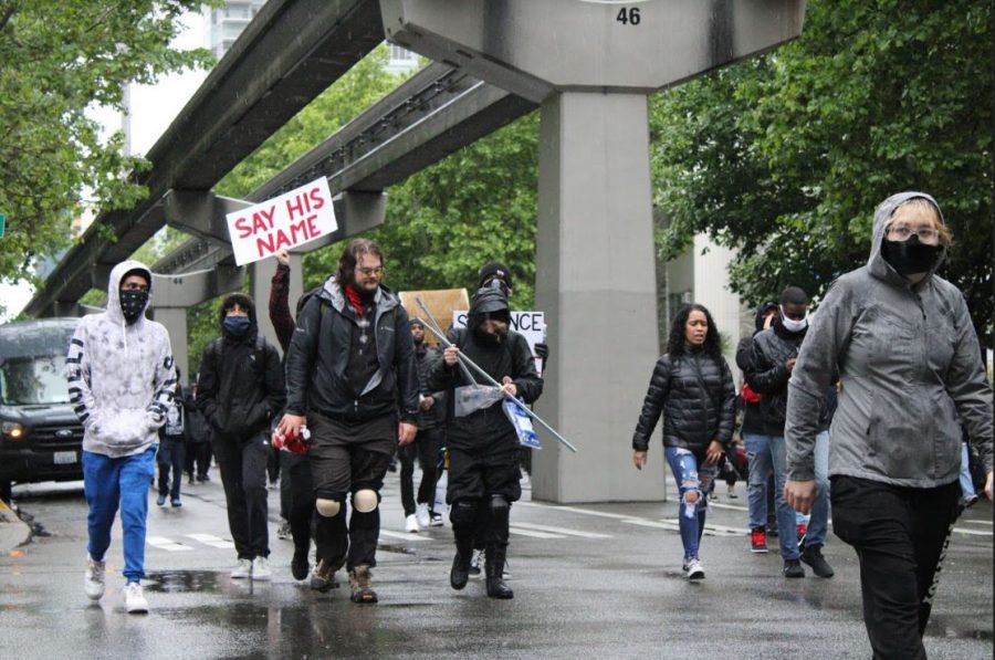 Black+Lives+Matter+protesters+marching+down+the+streets+of+downtown+Seattle+on+May+30%2C+2020.+One+of+them+holds+a+sign+that+says+say+his+name%2C+in+reference+to+the+police+brutality+case+of+George+Floyd.+