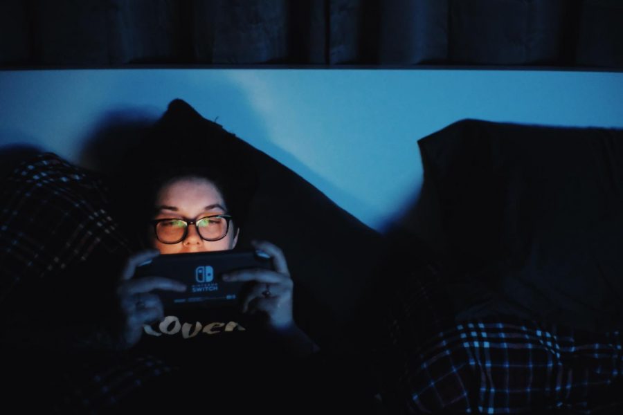 Leeanna Digruccio, an EvCC Student, is playing games on her Nintendo Switch in a darkly lit room.