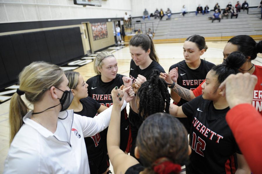 Coach Cheryl Sorenson (white) in a pre-game huddle before tip off of the first game of the season at Peninsula CC on April 3, 2021. EvCC won 48-43.