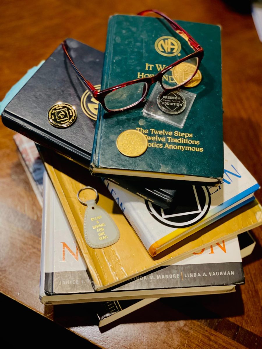 Textbooks, 12-step program literature and coins that represent time spent in recovery.