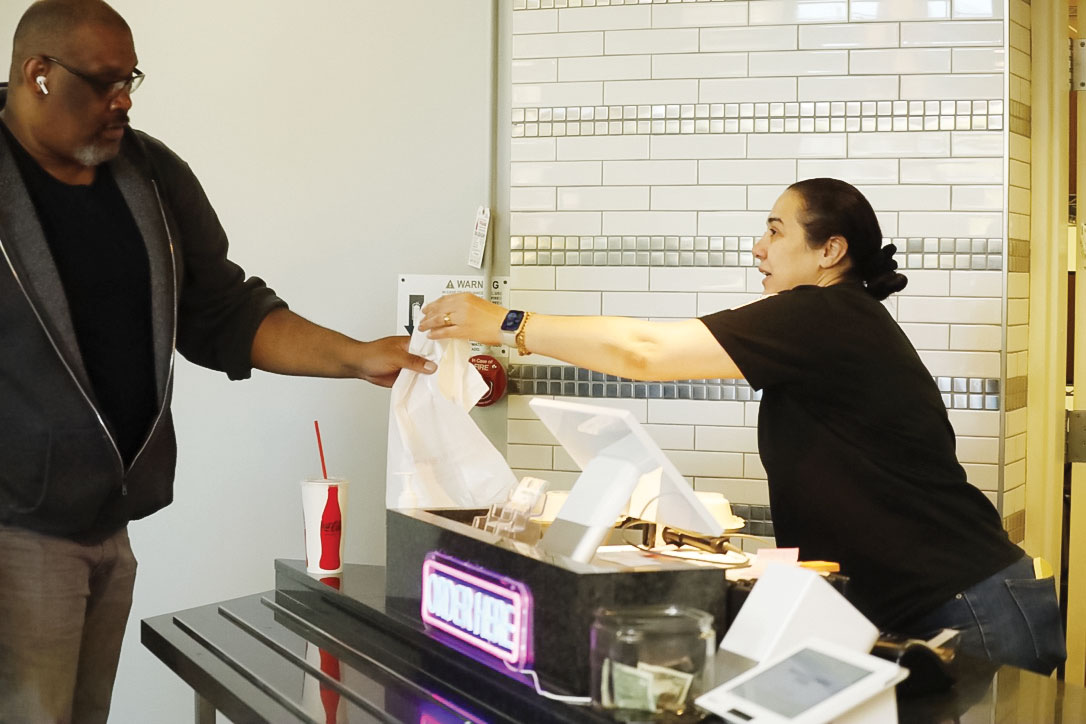 Nisreen Al-Ramahi loves providing food and smiles to students, as she does with Brian-Acheron Hedgepeth.